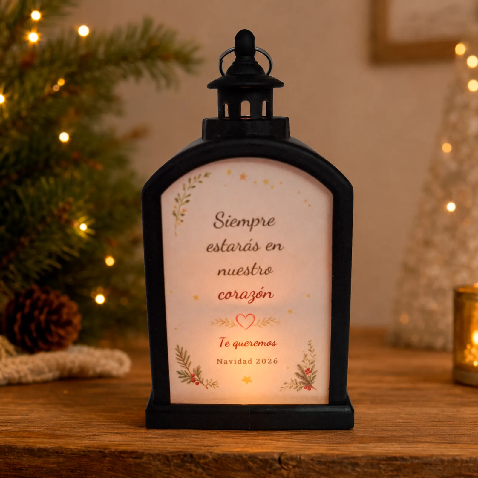 Farolillo LED negro conmemorativo con la dedicatoria «Siempre estarás en nuestro corazón», encendido en un ambiente navideño cálido.