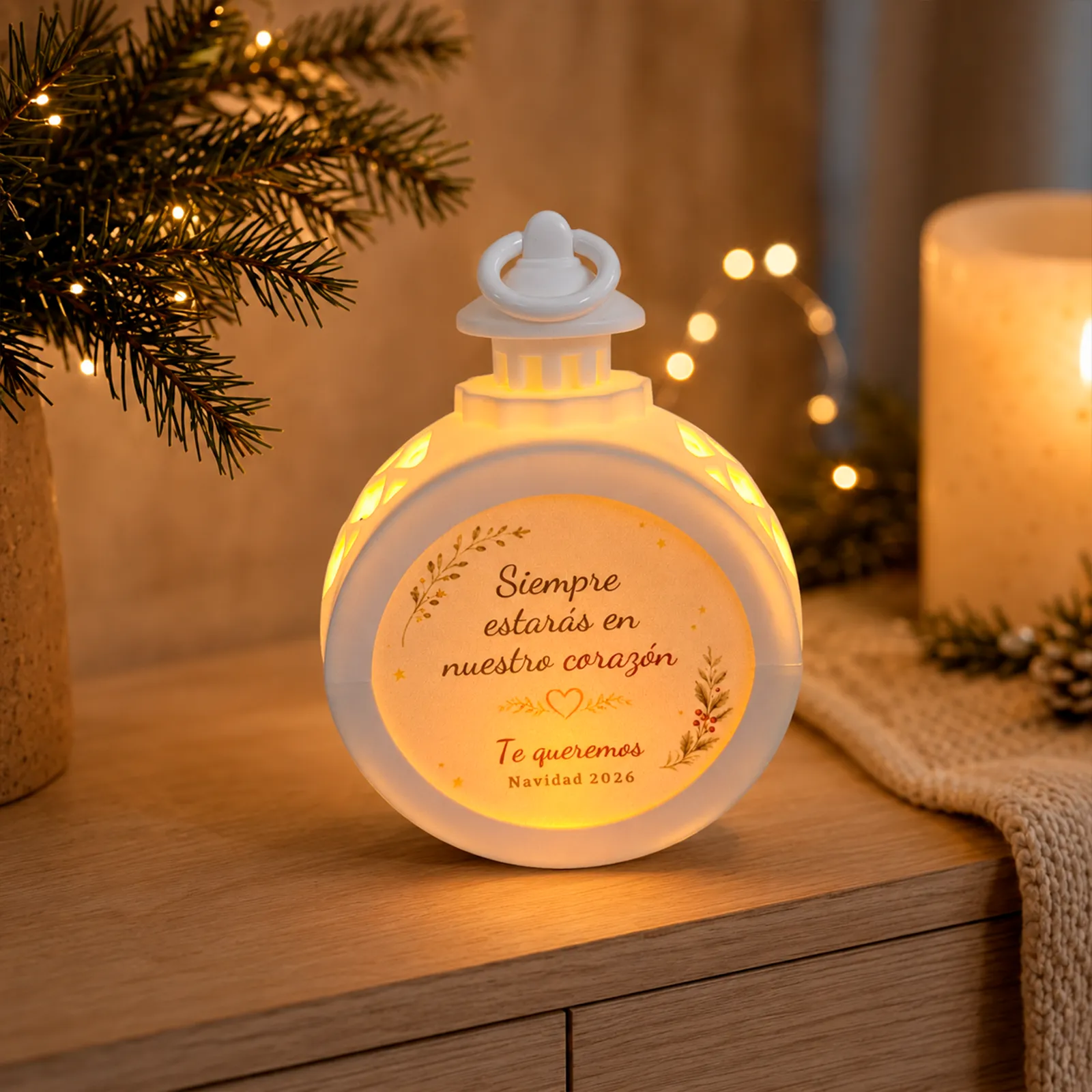 Farolillo LED redondo blanco conmemorativo con la dedicatoria «Siempre estarás en nuestro corazón», encendido en un ambiente navideño cálido.