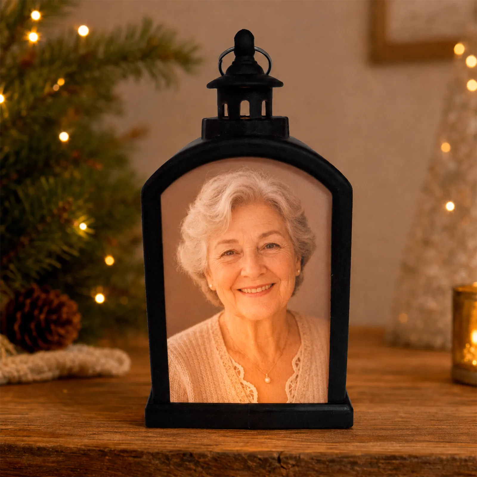 Farolillo LED negro conmemorativo personalizado con la fotografía de una señora mayor sonriendo, encendido en un ambiente navideño cálido.