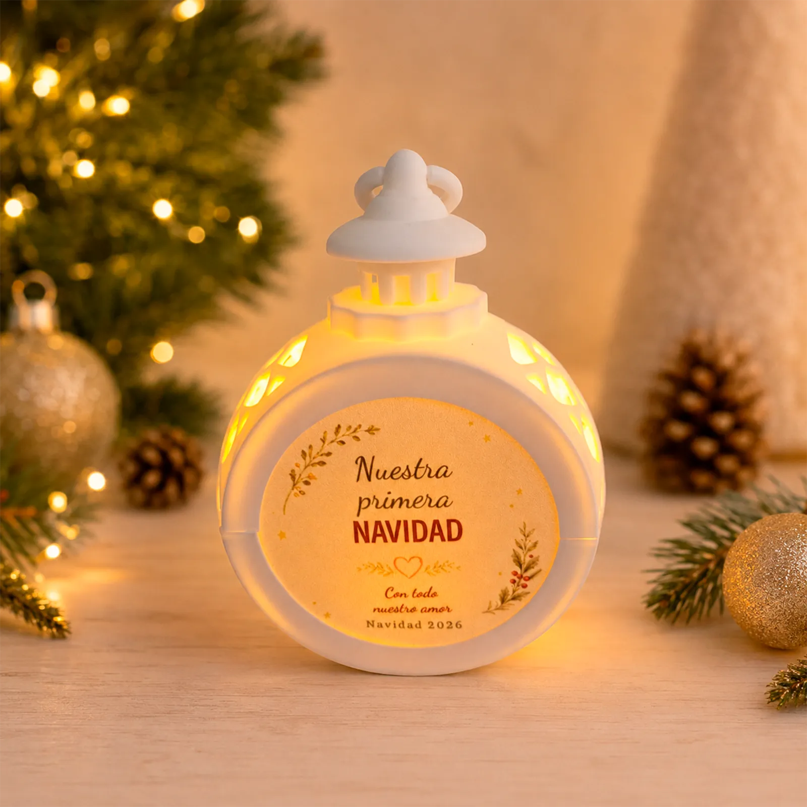 Farolillo LED redondo blanco personalizado con el diseño «Nuestra primera Navidad», dedicatoria y fecha, encendido en un ambiente navideño.
